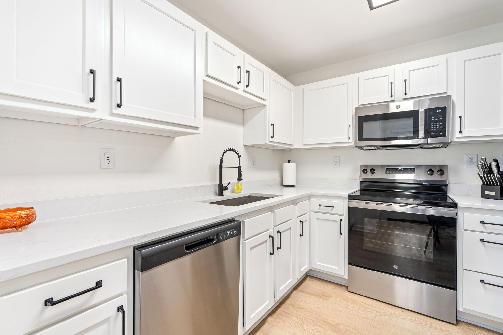 A modern kitchen with white cabinets, stainless steel appliances, and a dishwasher.