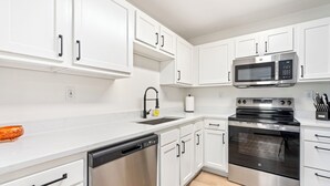 Una cucina moderna con mobili bianchi, elettrodomestici in acciaio inossidabile e lavastoviglie.
