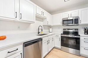 Una cocina moderna con armarios blancos, electrodomésticos de acero inoxidable y lavavajillas.