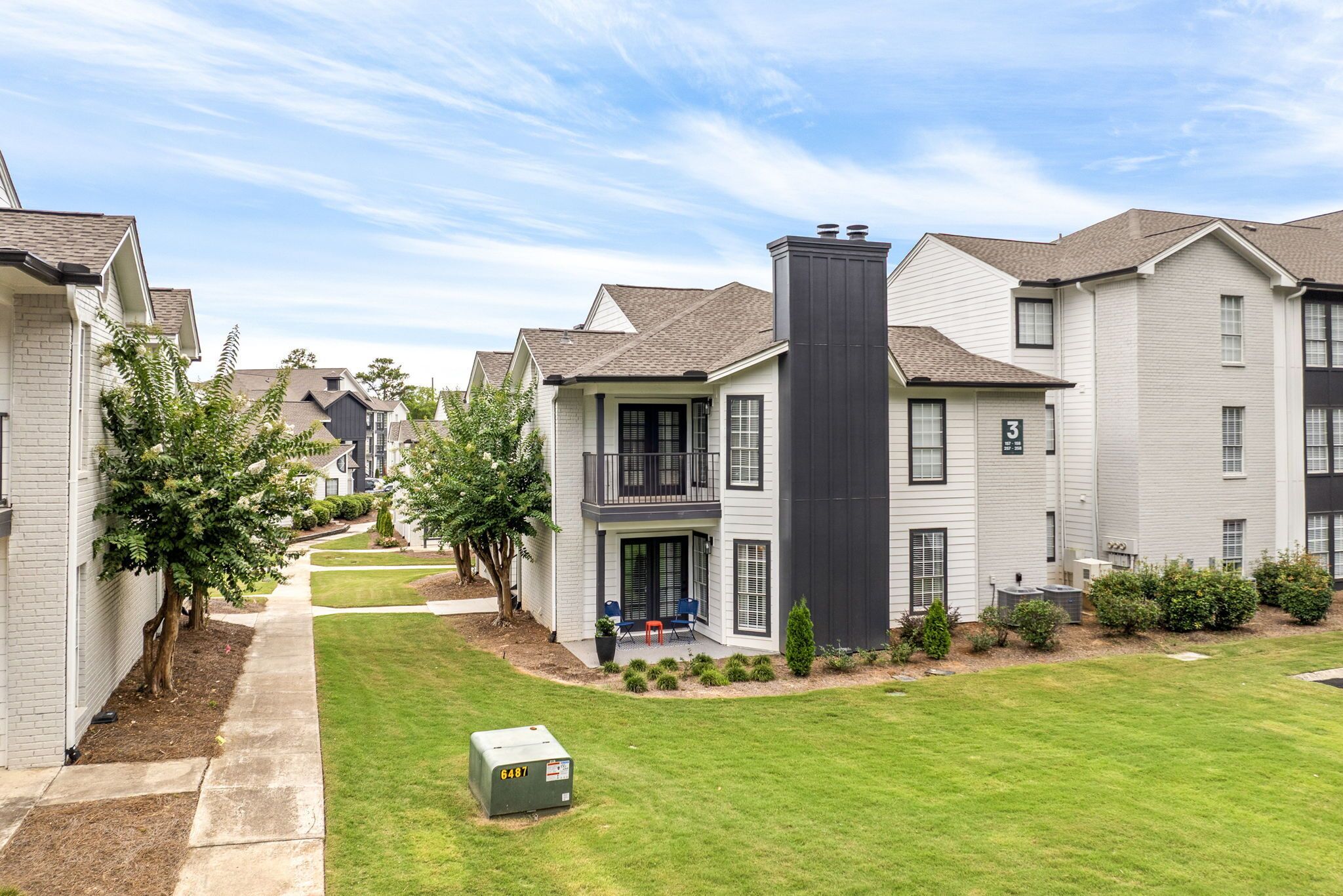 A residential complex with multiple two-story houses, a central courtyard with a lawn, and a pathway leading through the buildings.