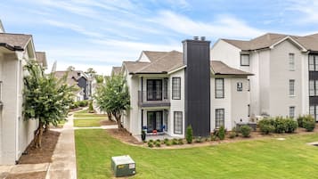 A residential complex with multiple two-story houses, a central courtyard with a lawn, and a pathway leading through the buildings.