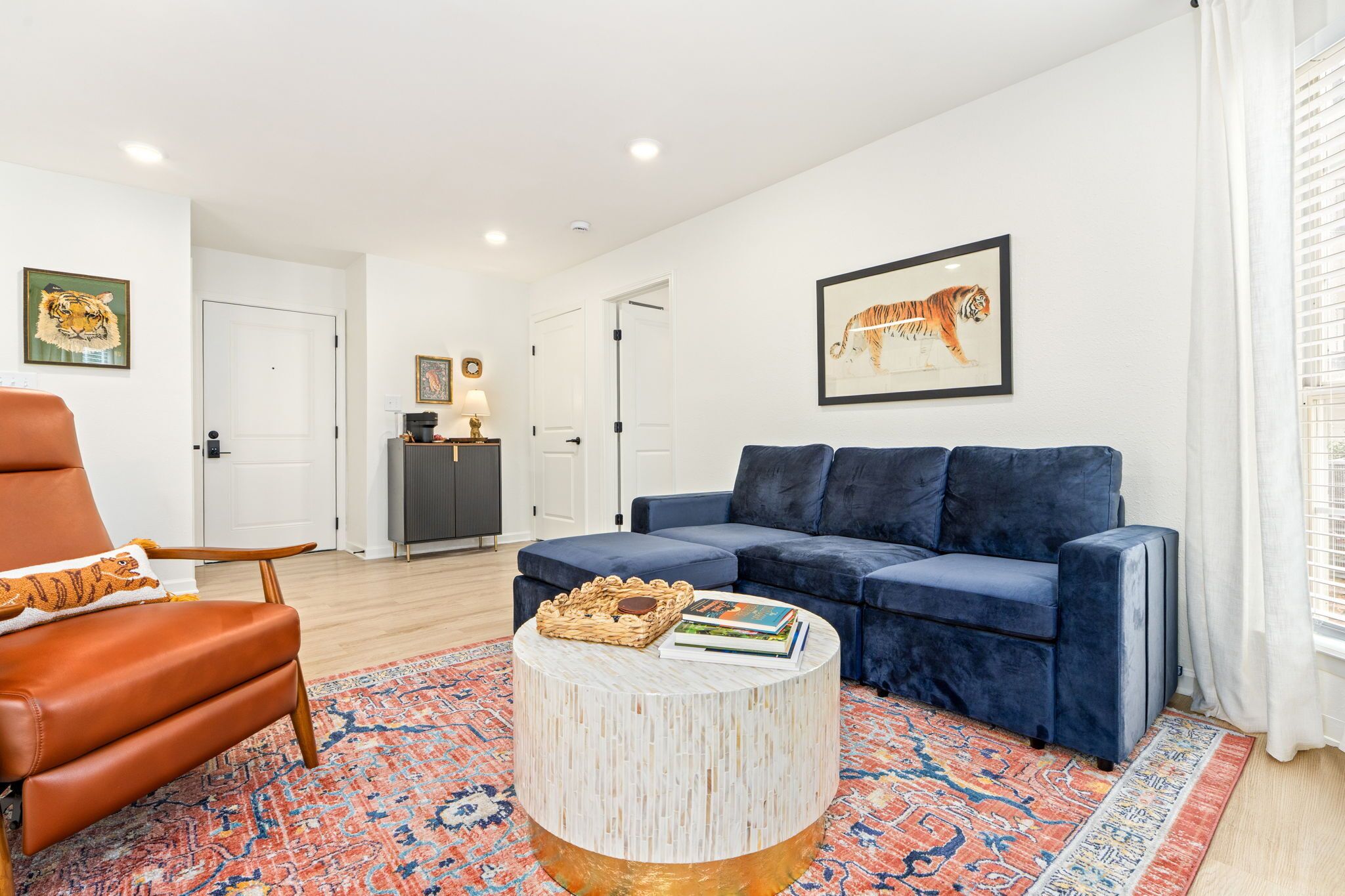 Un salon moderne avec un fauteuil en cuir, un canapé bleu et une table basse ronde sur laquelle sont posés des livres.