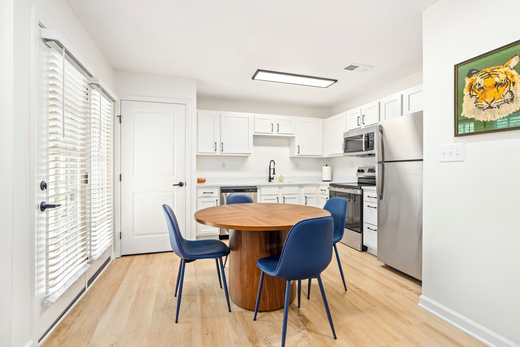 Una cocina moderna con armarios blancos, una isla central con sillas y un refrigerador de acero inoxidable.