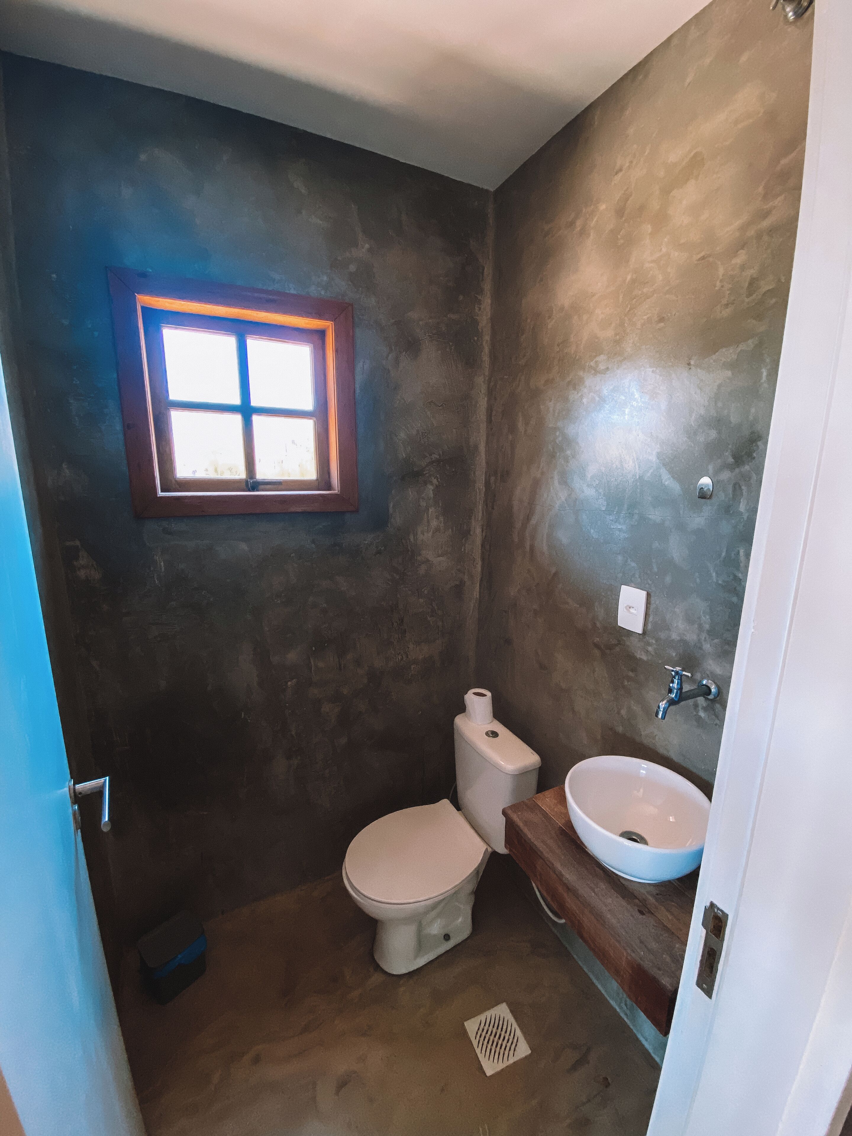 A small bathroom with a toilet, sink, and a window.