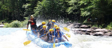 A group of people in a blue raft navigating through a river with rapids.