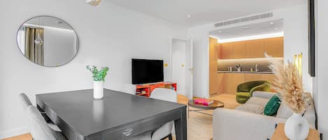 Una sala de estar moderna con una mesa de comedor, sofá y televisor.