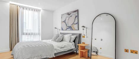 Un dormitorio moderno con cama, un espejo grande y una ventana con cortinas.