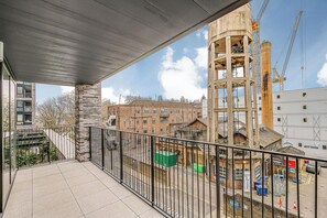 A balcony with a view of a construction site, a brick building, and a crane. - AC | Private Balcony | Gym  | StayCozy (London)
