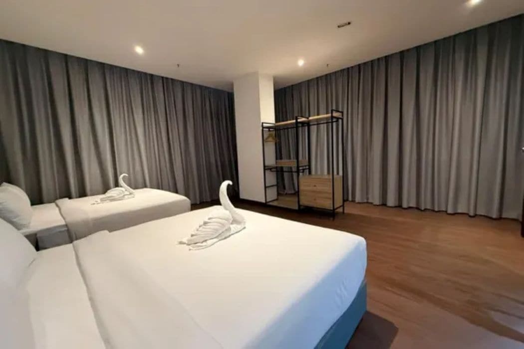 A hotel room with a large bed, a smaller bed, and a seating area with a bench.