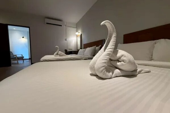 A hotel room with two beds, a large swan-shaped towel decoration, and a view of the outside.