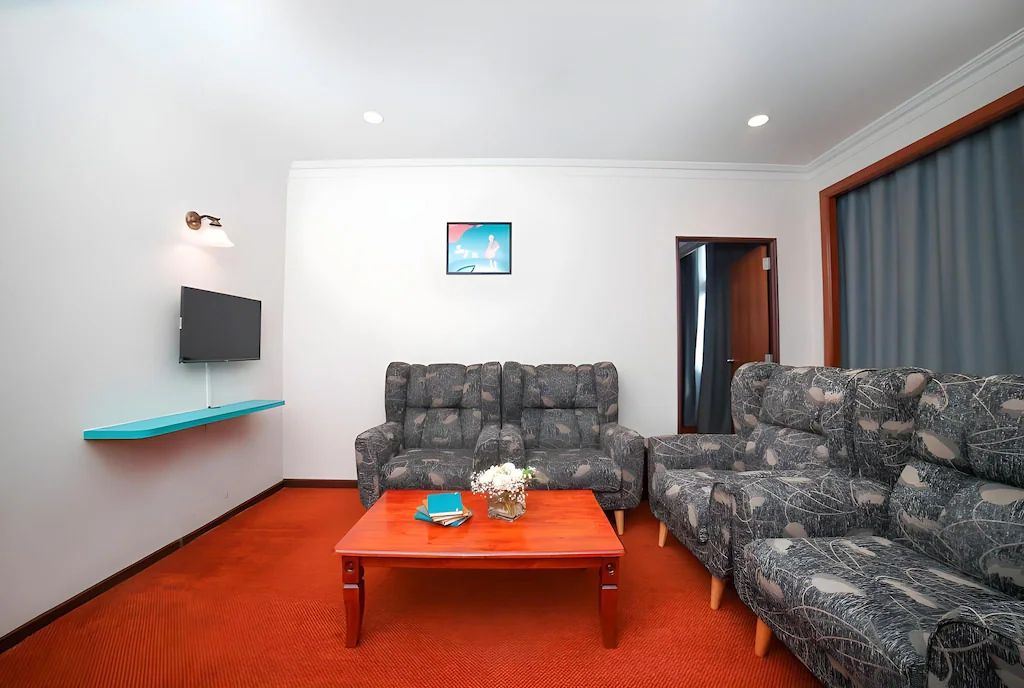 Ein Wohnzimmer mit einer Couch, einem Couchtisch, einem Flachbildfernseher und einem an der Wand montierten Regal.