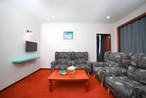 A living room with a sofa, a coffee table, a flat-screen TV, and a wall-mounted shelf. - Kingston Hotel 21 - JO Hotel Johor Bahru (Johor Bahru)