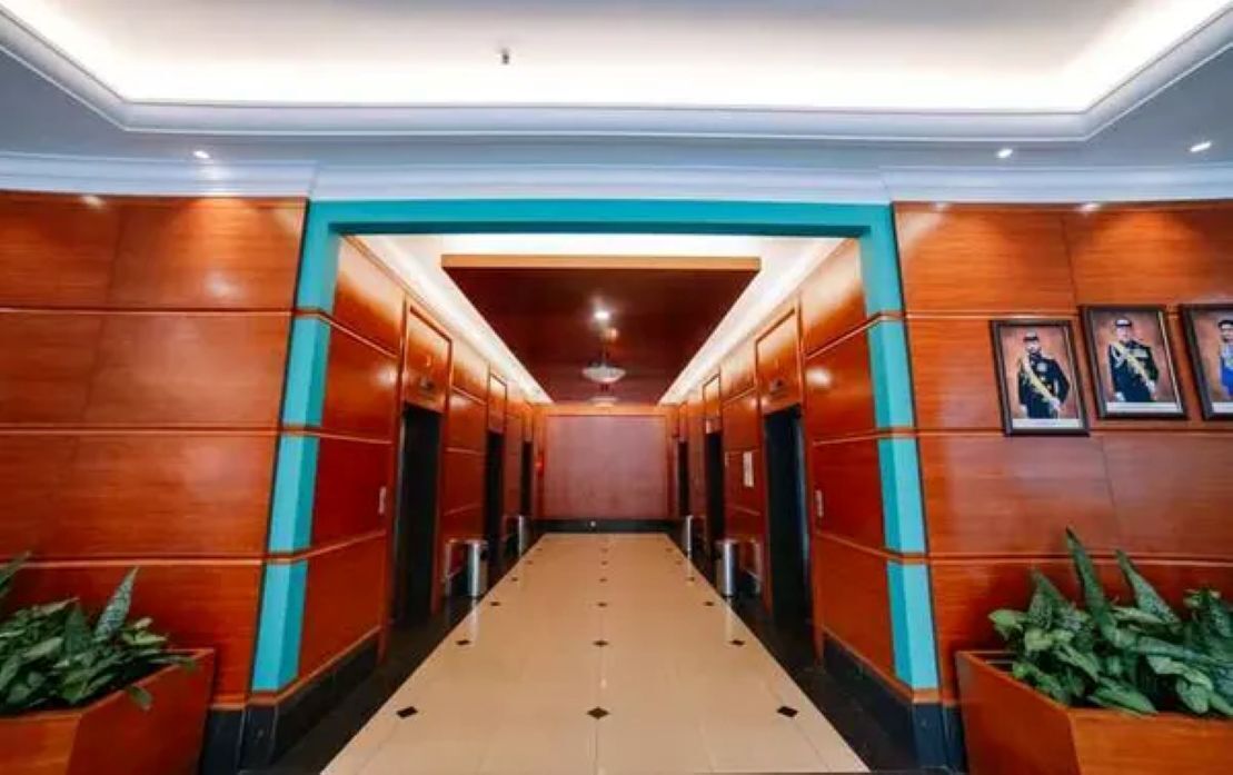 A hotel corridor with wooden paneling, a tiled floor, and framed portraits on the walls.