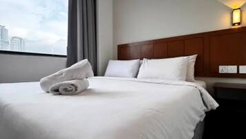 Quarto de hotel com cama bem arrumada, cabeceira e janela com cortinas.