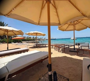 Eine Strandlounge mit Liegestühlen und Sonnenschirmen mit Blick aufs Meer.