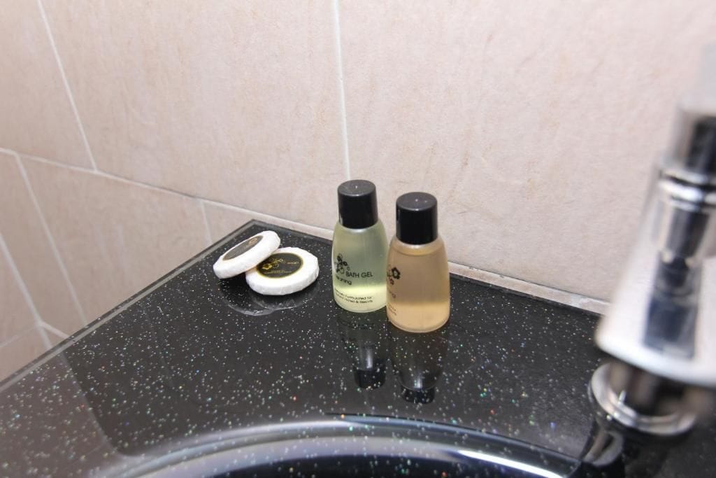 A bathroom sink with two bottles of bath gel and a pair of white earplugs on the countertop.