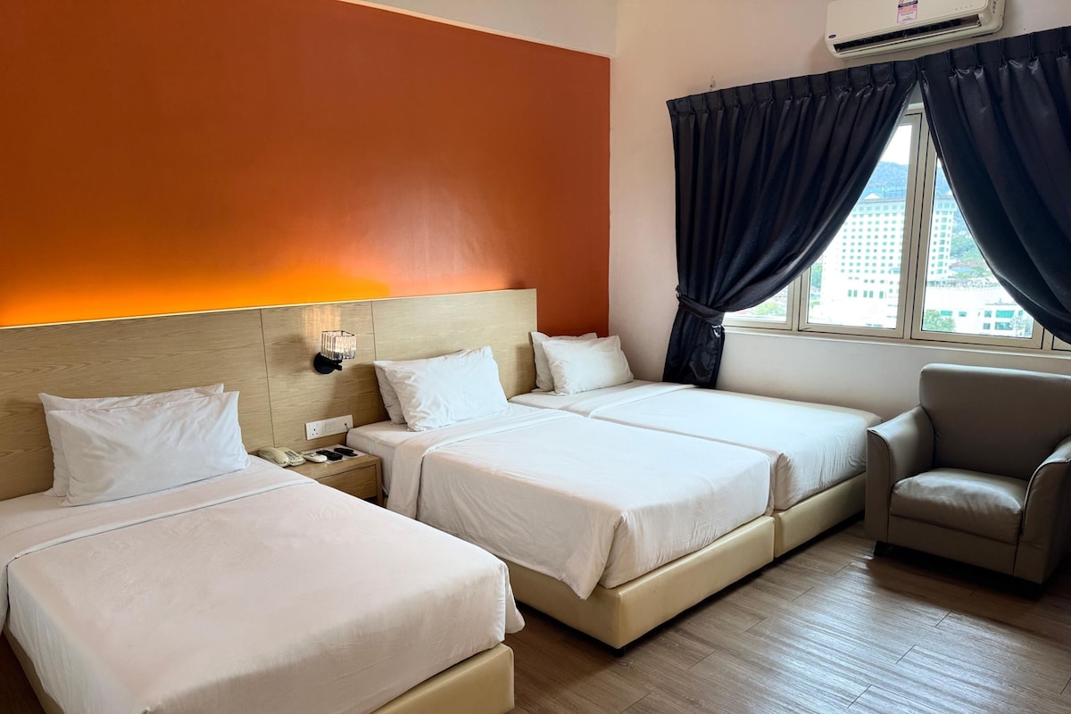 Habitación de hotel con dos camas, una mesita de noche, una silla y un ventanal con cortinas.