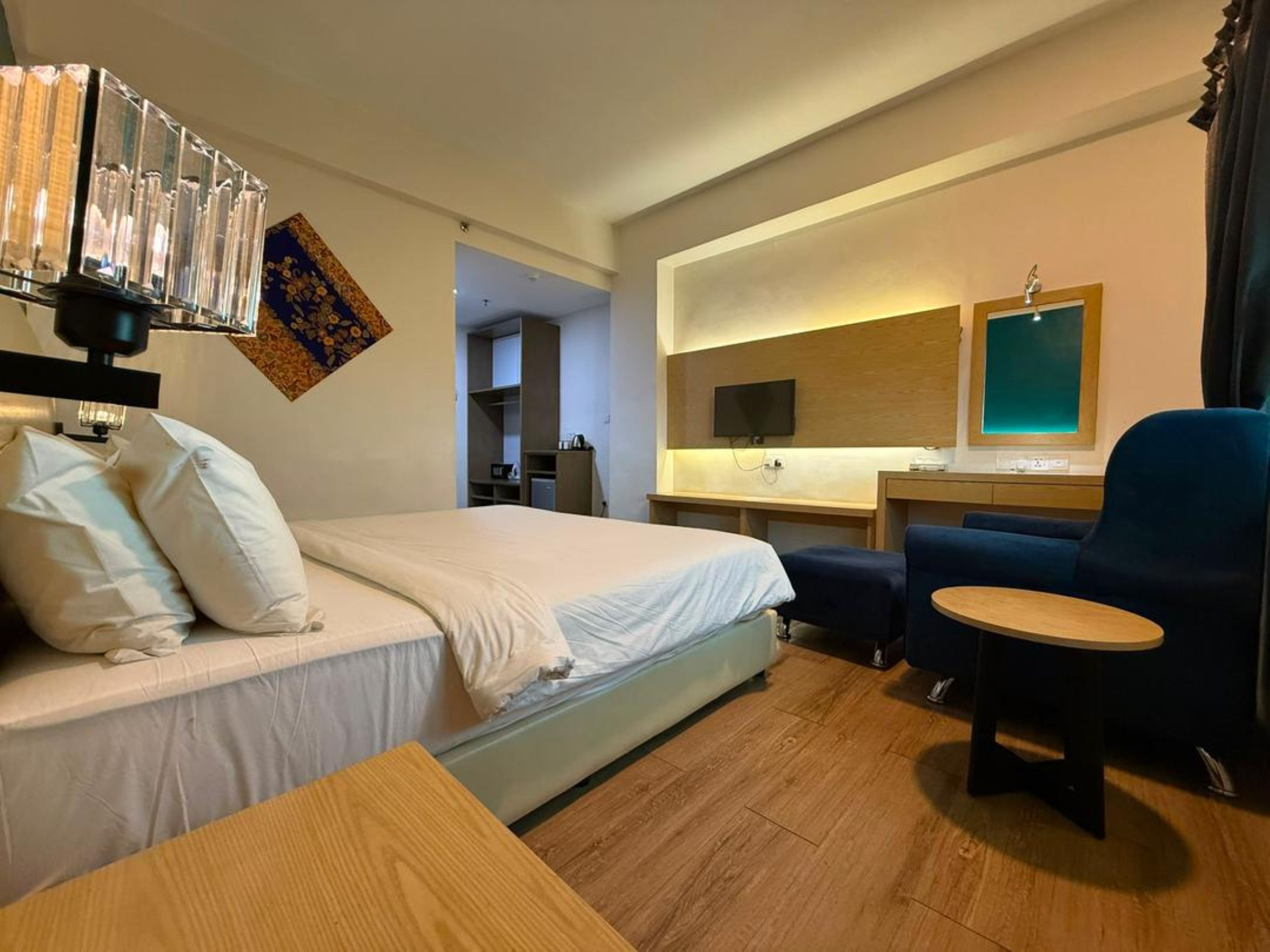 Una habitación de hotel con una cama, un escritorio, una silla y un televisor.