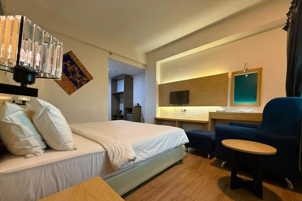 Una habitación de hotel con una cama, un escritorio, una silla y un televisor.