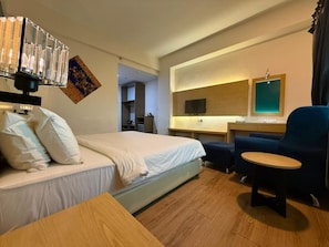 Una habitación de hotel con una cama, un escritorio, una silla y un televisor.