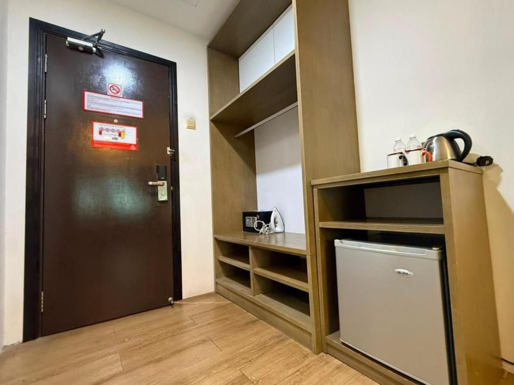 A hotel room with a wooden door, a minibar, and a small refrigerator.