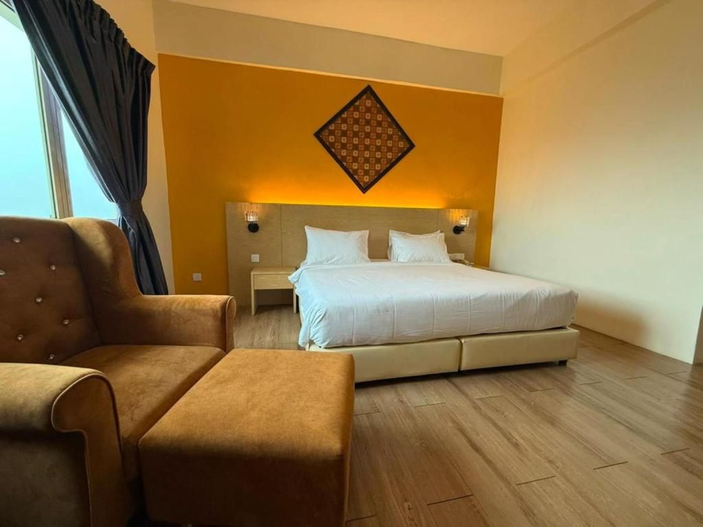 A hotel room with a bed, a sofa, a nightstand, and a wall-mounted light fixture.
