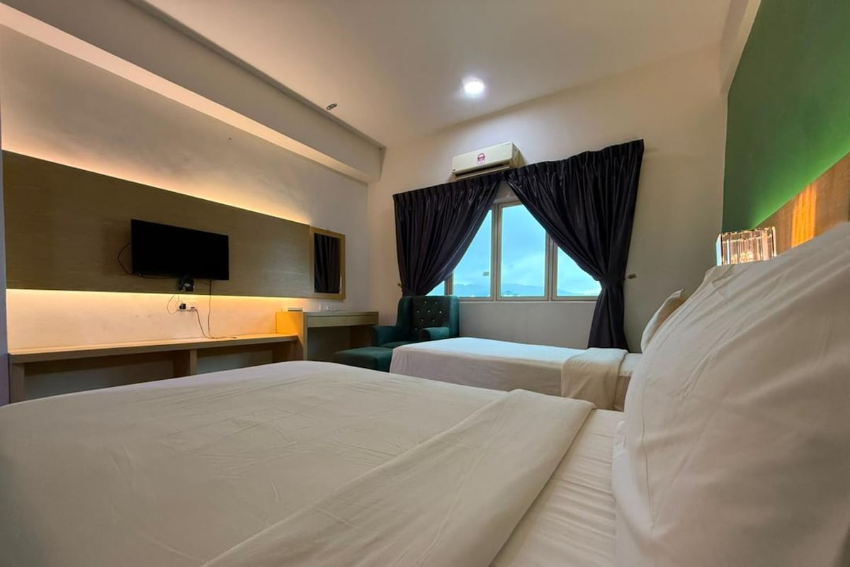 Habitación de hotel con dos camas, un escritorio, una silla, un televisor y una ventana con cortinas.