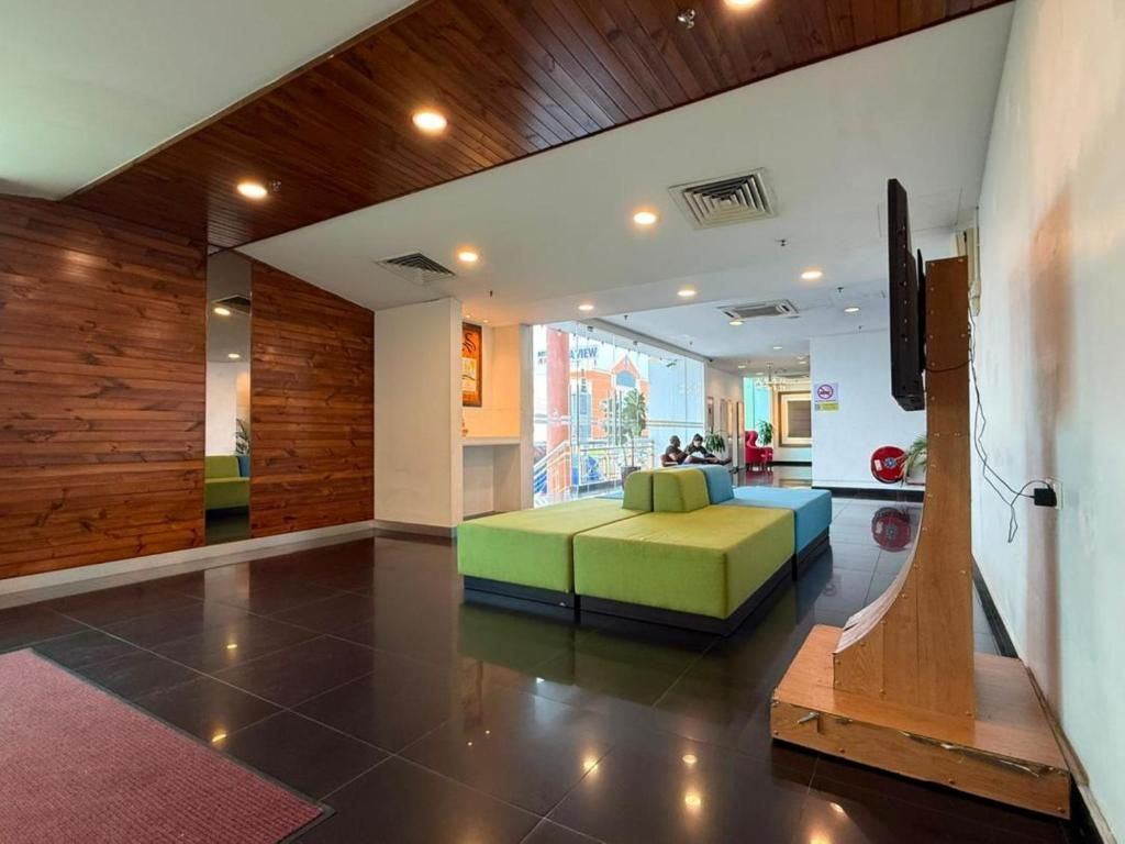Un hall d’entrée moderne avec un plafond en bois, un canapé vert et un élément de décoration circulaire rouge.
