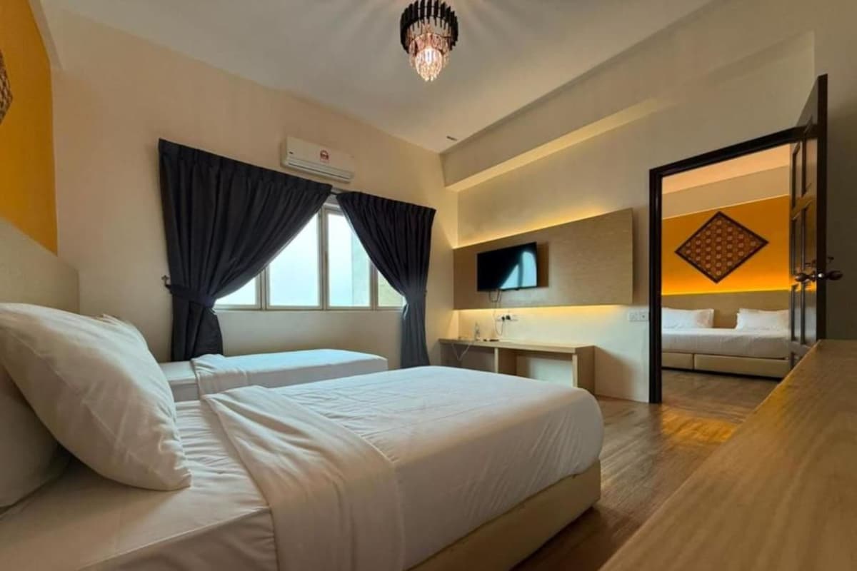Habitación de hotel con dos camas, televisión, escritorio y vistas al exterior.