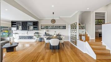 A modern kitchen with a dining area, wooden flooring, and a staircase leading to an upper level.
