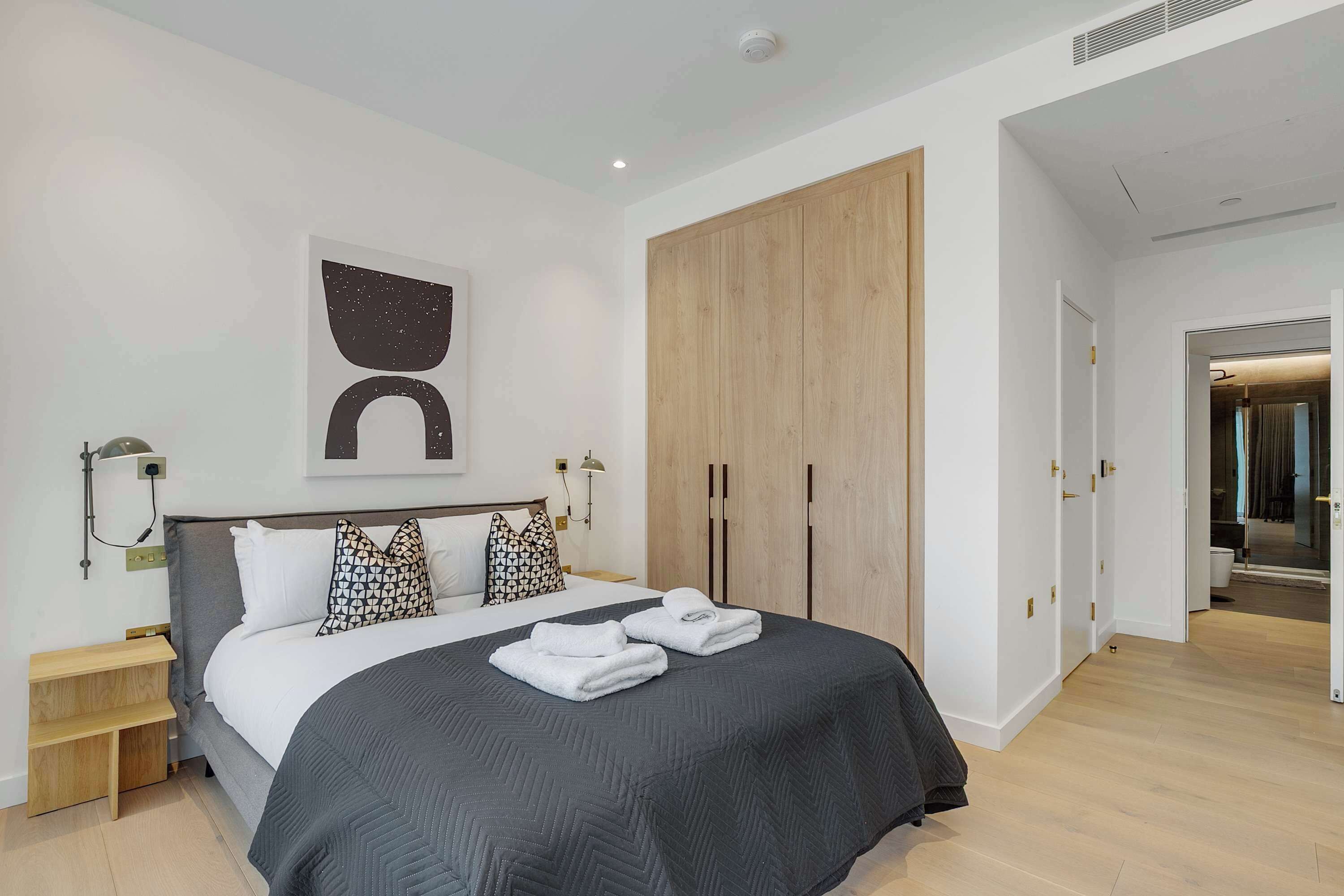Un dormitorio moderno con una cama grande, un armario y una mesita de noche.