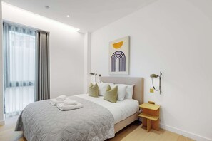 Una camera d'albergo moderna con un grande letto, un comodino, una scrivania e una finestra con tende.