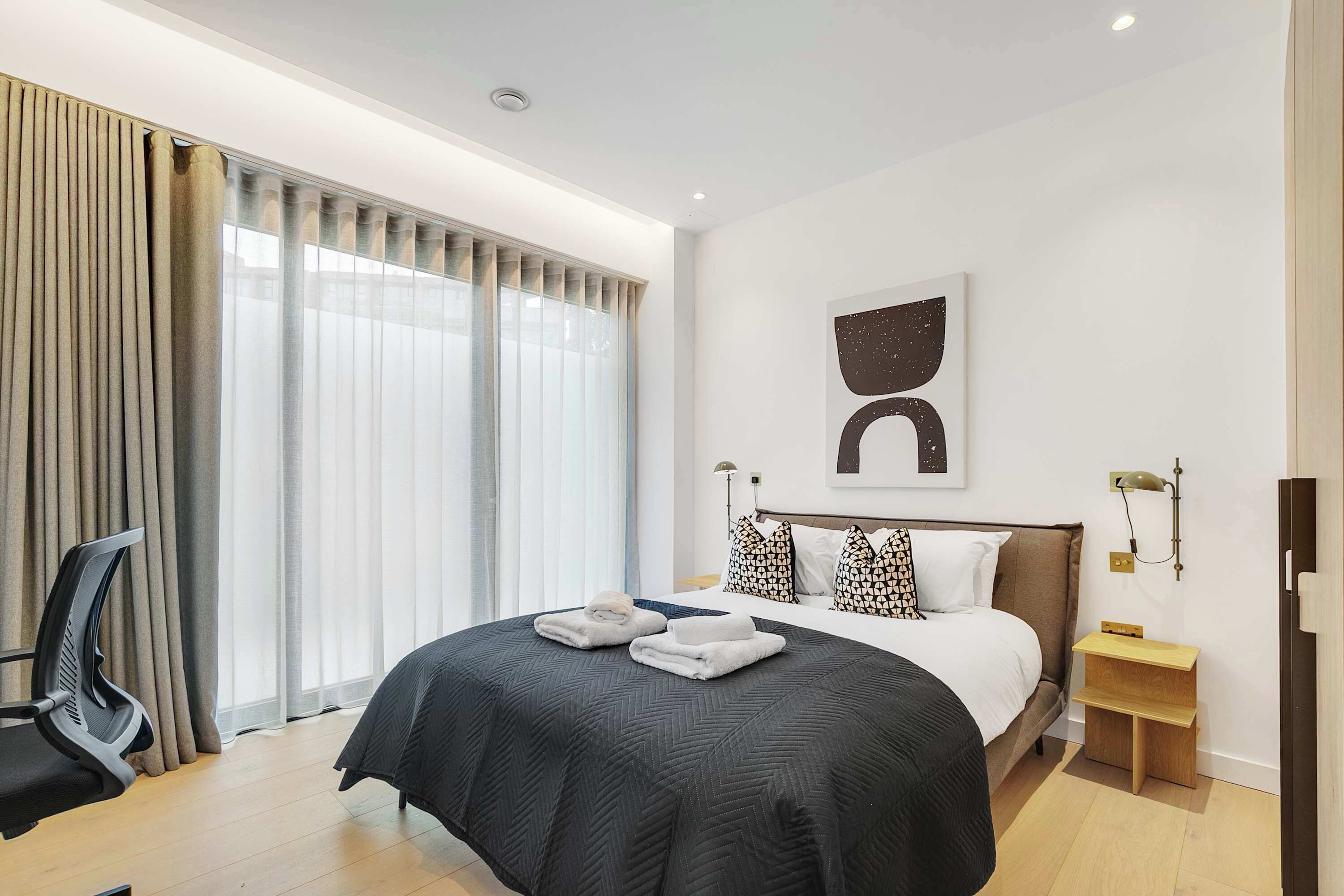 Une chambre d’hôtel moderne, dotée d’un grand lit, d’un bureau et d’une chaise.