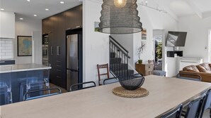 Una cocina moderna con una isla central, muebles oscuros y una lámpara colgante.