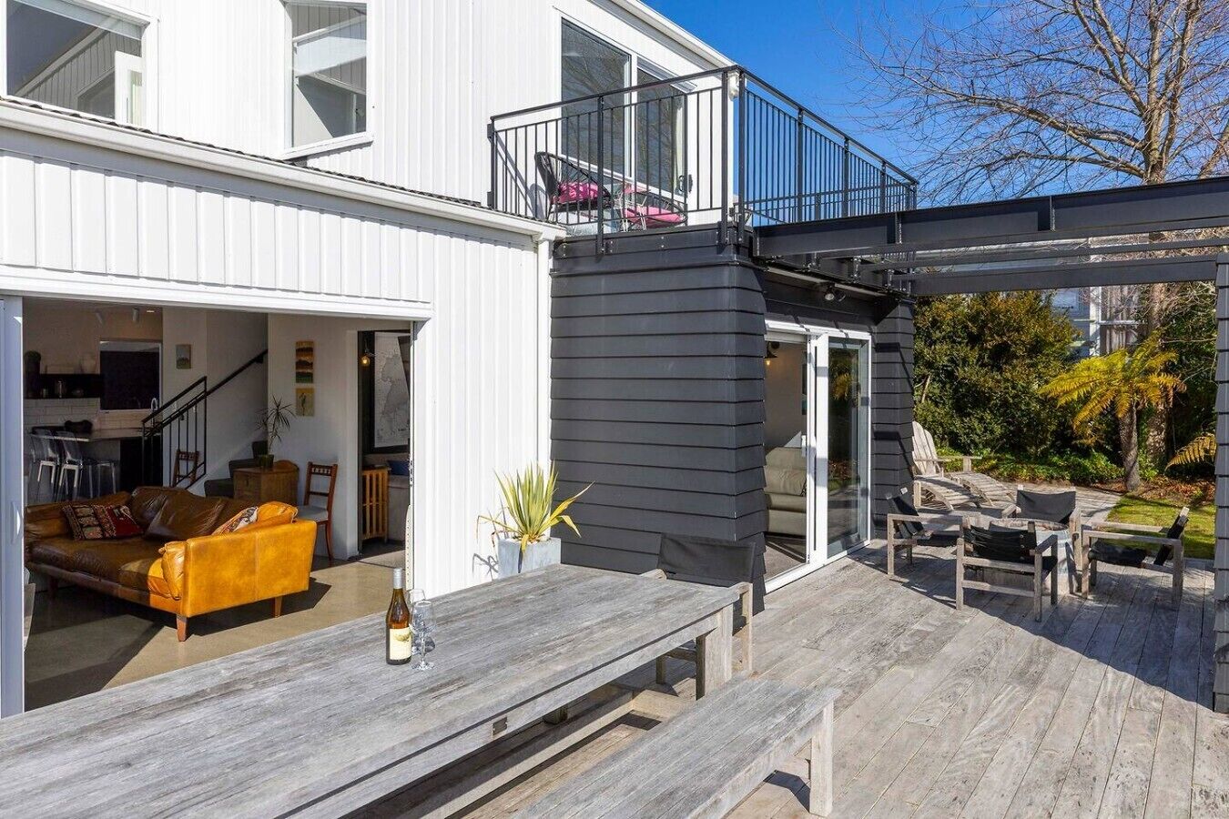 Een modern huis met een overdekte patio, een eethoek en een woonkamer met een bank en stoelen.