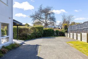Ein gepflasterter Weg führt zu einem Haus mit einer überdachten Veranda und einem umzäunten Garten.