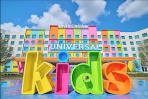 Ein buntes Gebäude mit der Aufschrift 'UNIVERSAL Kids' und einem Poolbereich davor.