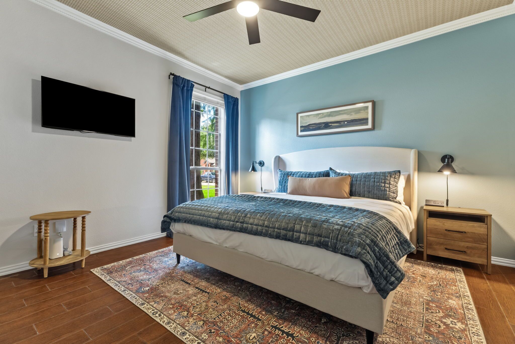 Une chambre à coucher avec un lit, une table de chevet, un téléviseur et un ventilateur de plafond.