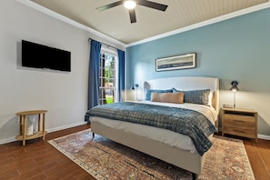 Ein Schlafzimmer mit Bett, Nachttisch, Fernseher und Deckenventilator.