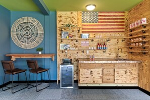 Eine Bar mit Holztresen, Barhocker und einer großen amerikanischer Flagge.