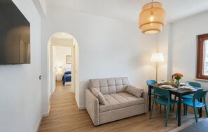 A modern living room with a sofa, dining table, chairs, a lamp, and a television. - Maison marina Suite - Corfù (Paola)
