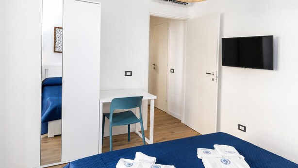 A hotel room with a bed, a desk, a chair, a television, and a wardrobe. - Maison marina Suite - Corfù (Paola)