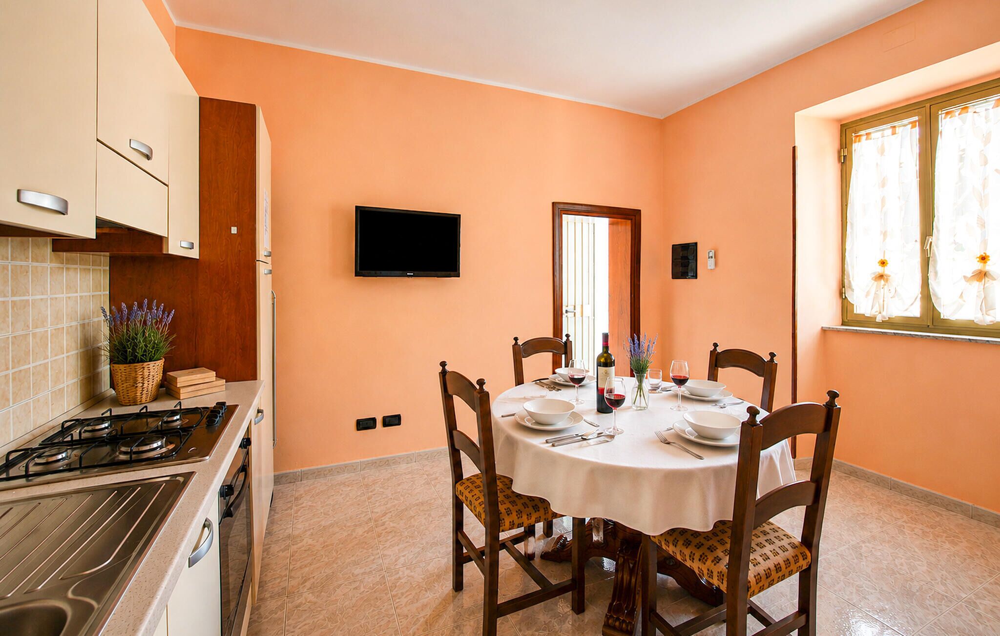 A dining area with a round table, chairs, and a TV mounted on the wall.