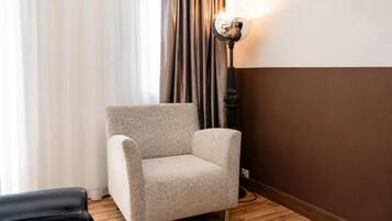 A room with a single armchair, a lamp, and a curtain.