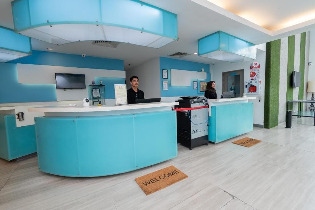 A reception area with a blue counter, a television mounted on the wall, and a welcome mat on the floor.