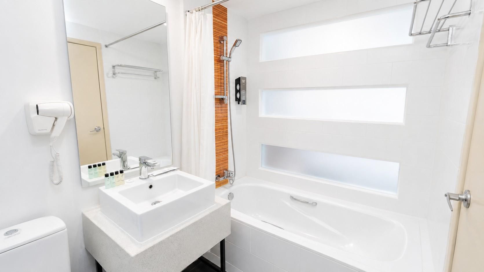 A modern bathroom with a white sink, mirror, and bathtub.
