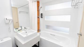 A modern bathroom with a white sink, mirror, and bathtub.