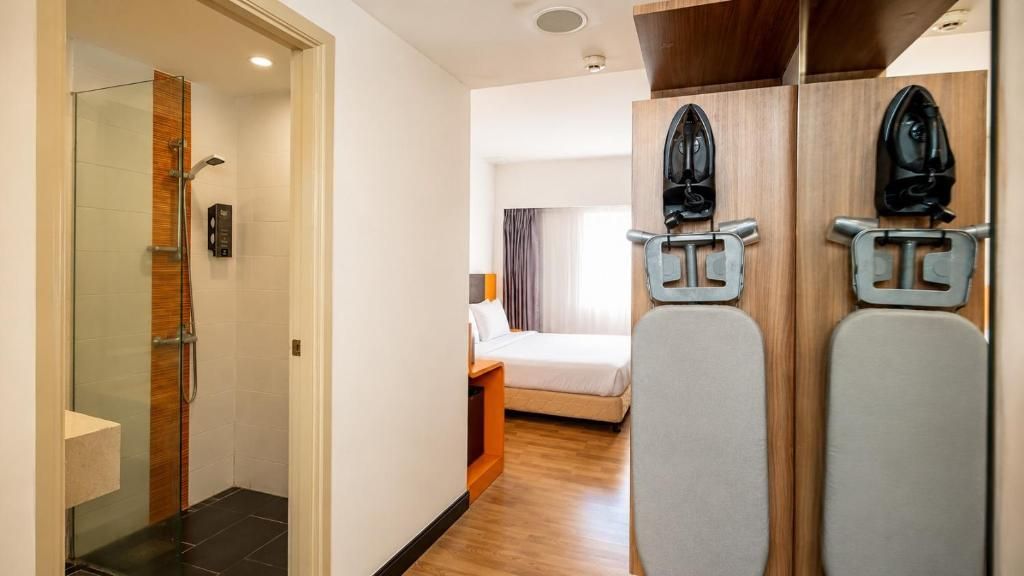 A hotel room with a shower, a bed, a bedside table, and a mirror.