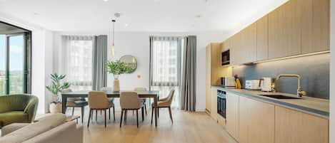 Una cocina moderna con armarios de madera, un comedor con mesa y sillas, y un amplio ventanal con cortinas.