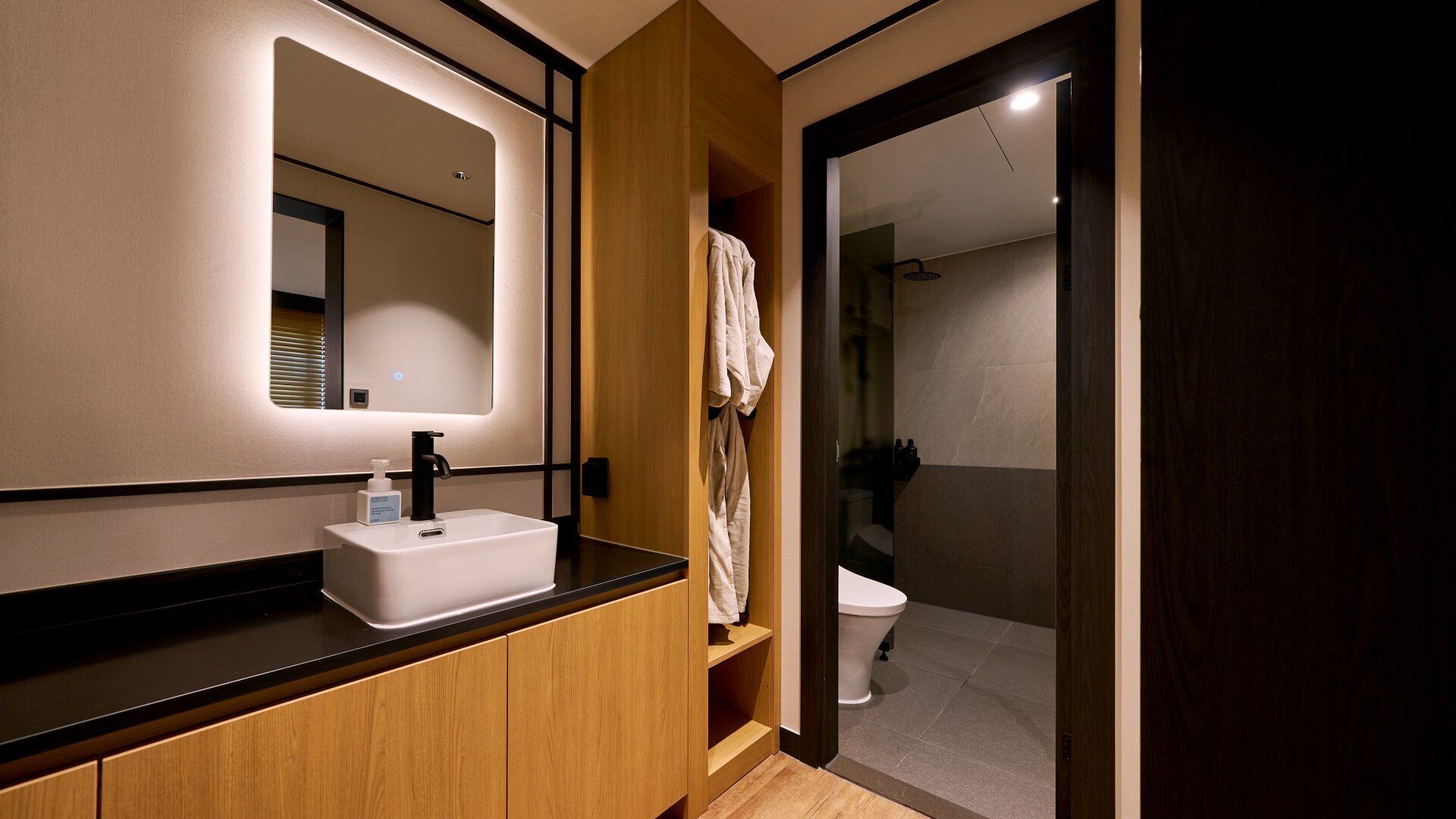 A modern bathroom with a vanity, a mirror, a toilet, and a shower area.